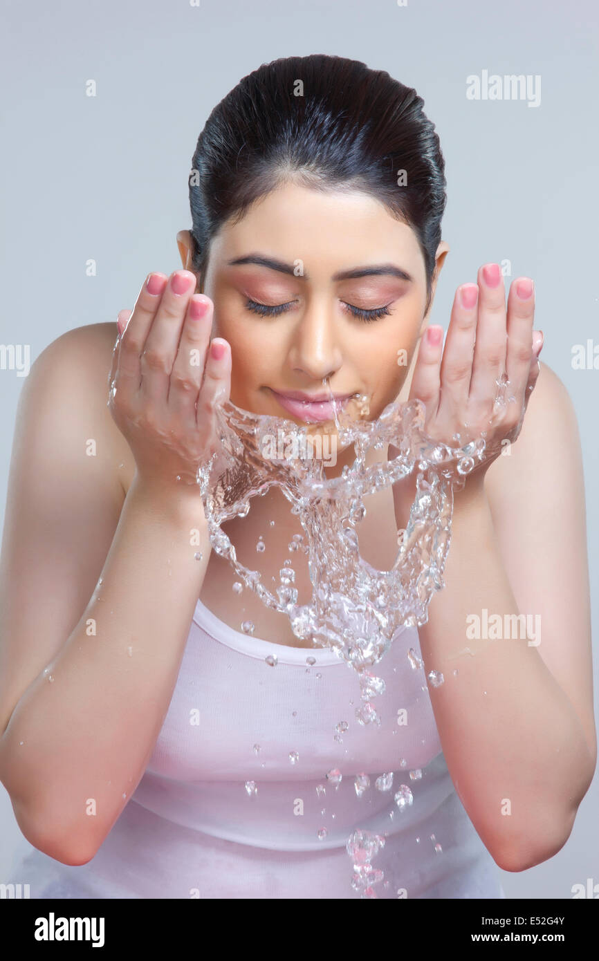 Young woman washing face with water over gray background Stock Photo Alamy