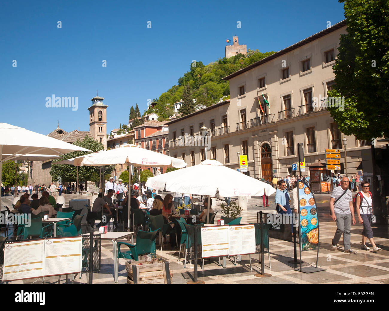 People in tourist cafe in Plaza Nueva, Granada, Spain looking up at part of the Alhambra on a hill top. Stock Photo