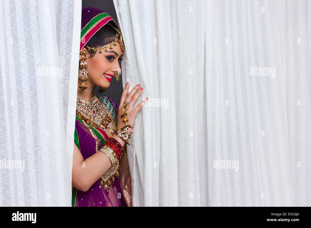 Beautiful shy bride standing amidst curtains Stock Photo Alamy