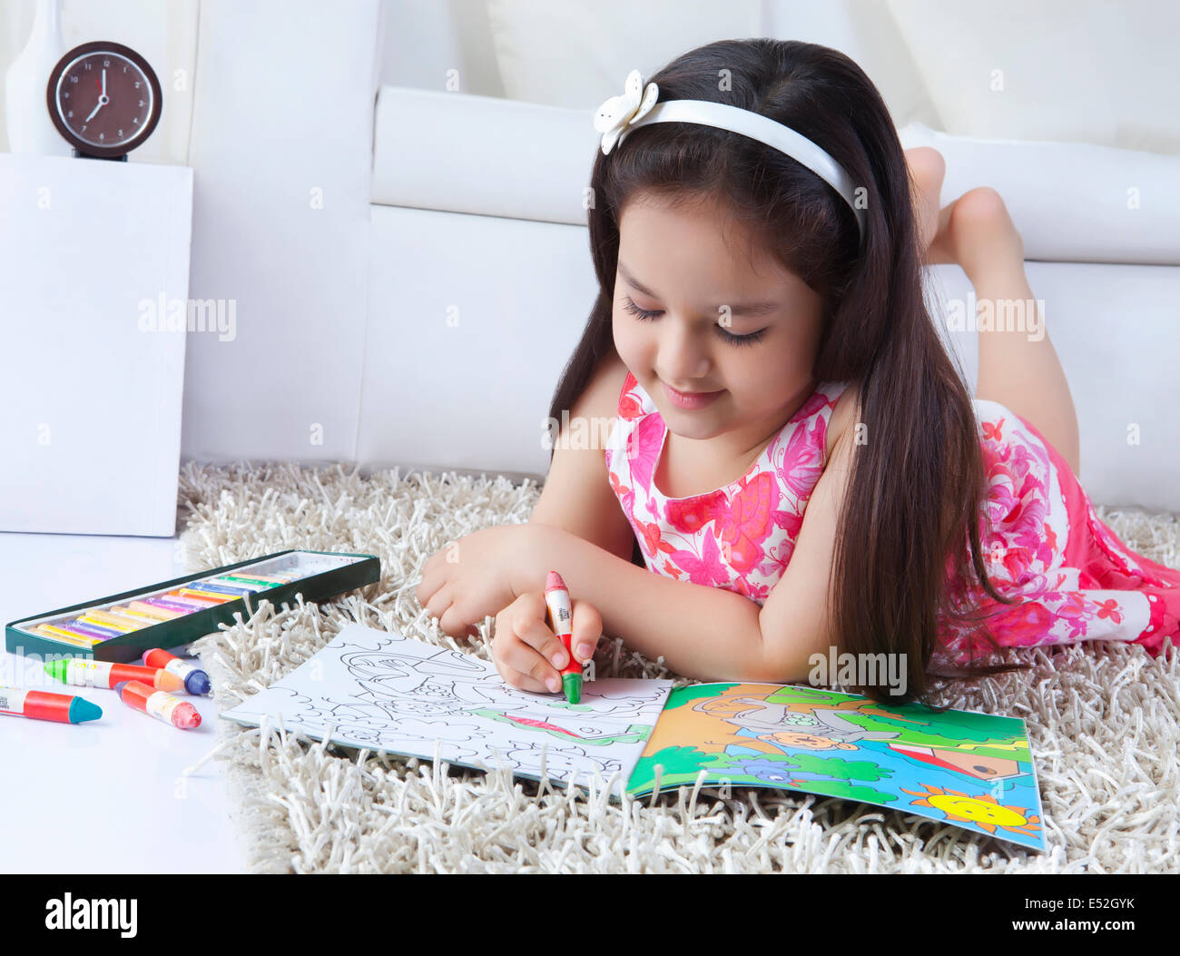 Girl drawing in book while lying on rug at home Stock Photo