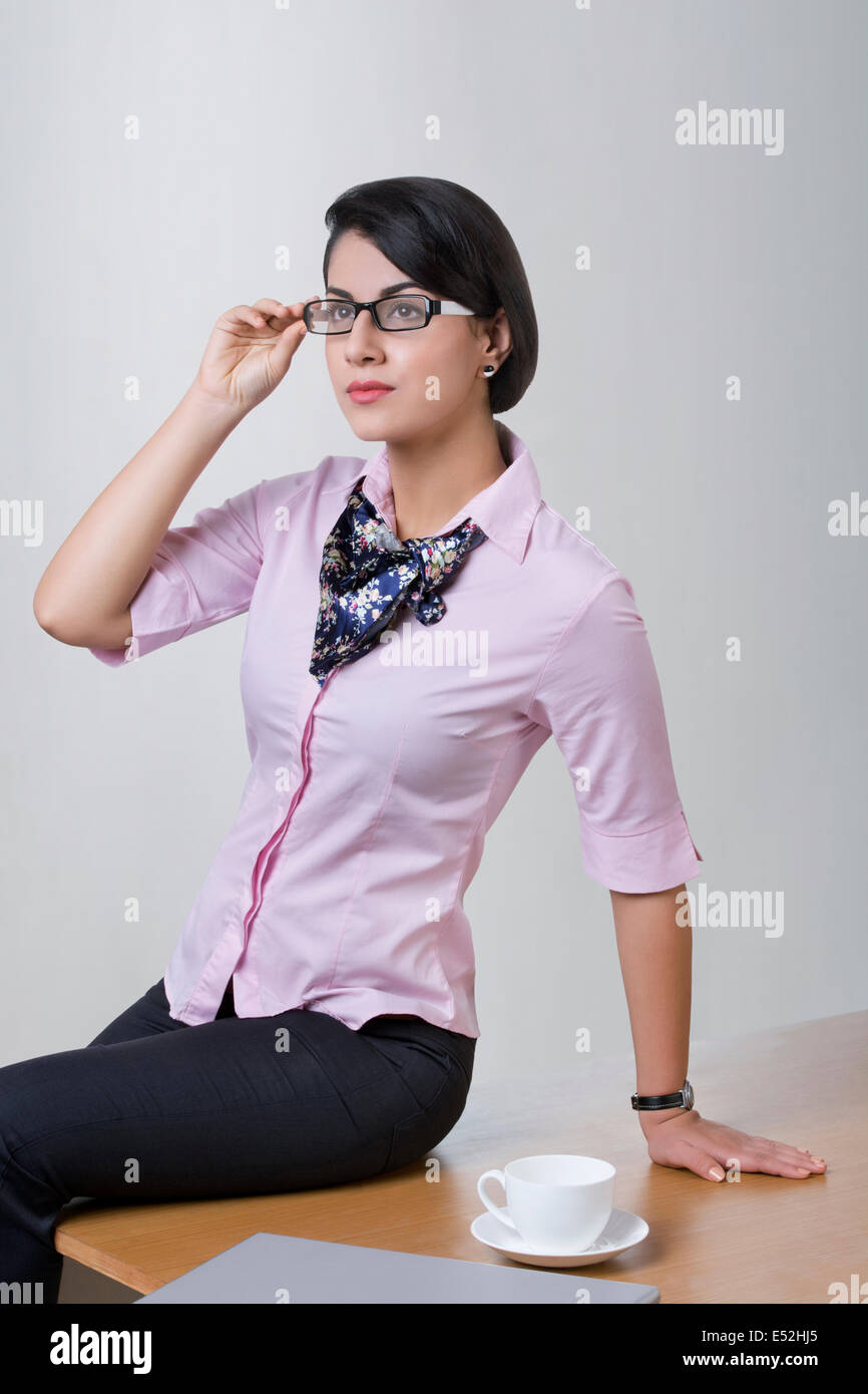 Confident Indian businesswoman sitting on office desk Stock Photo - Alamy