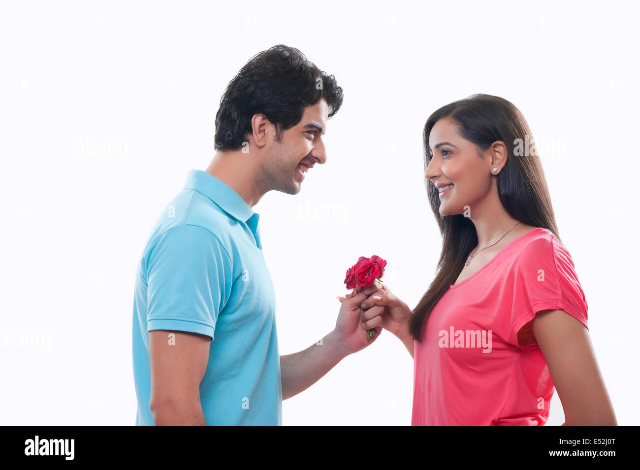 Side view of happy man giving rose to woman over white background Stock Photo