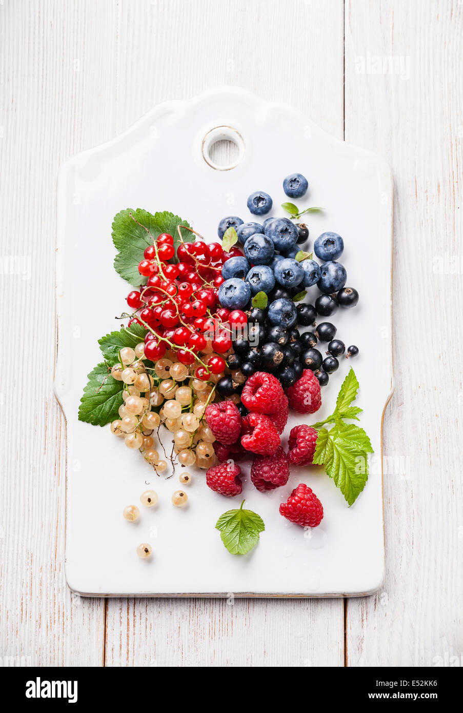 Mix of fresh berries with leaves on rustic wooden background Stock Photo