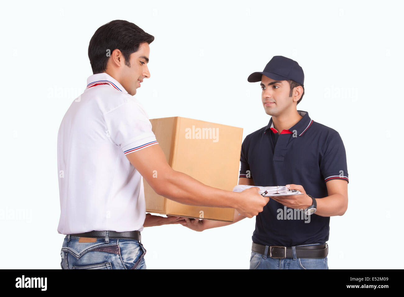 Male delivery person giving package to customer against white background Stock Photo