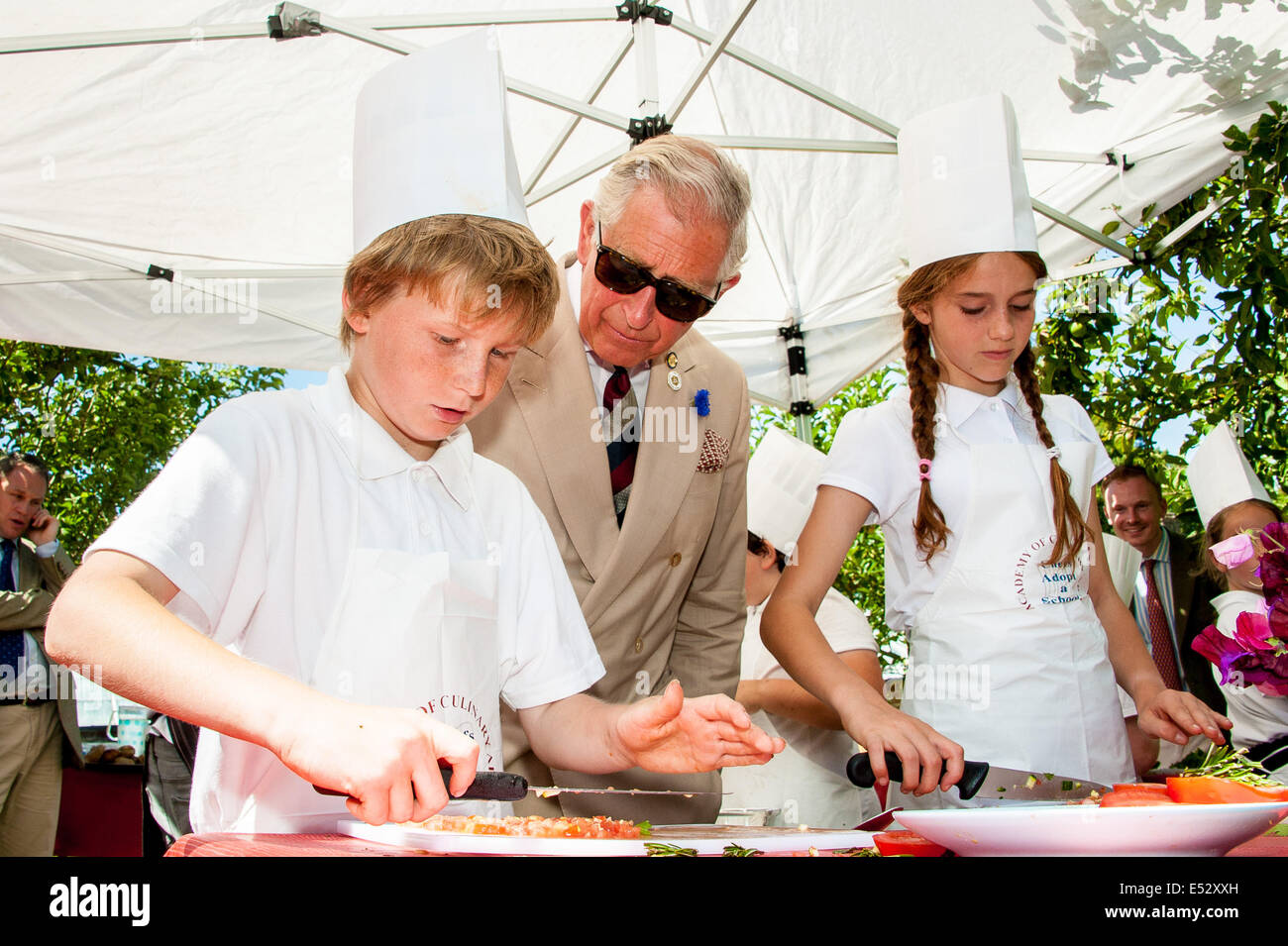 Wiston, West Sussex, UK. 18th July, 2014. HRH Prince Charles chats with children at Wiston House as they prepare lamb burgers under the tutelage of Peter Vaughan [of The Bistro, Devizes,]. The children from local Steyning Primary School's year 5 are taking part in a ‘Chef on the Farm’ day organised by Countryside Classroom. The organisation helps children to connect with where their food comes from. The children work with the gardener to source fresh produce, meet the farmers who rear the sheep, and cook with an expert chef Credit:  Julia Claxton/Alamy Live News Stock Photo