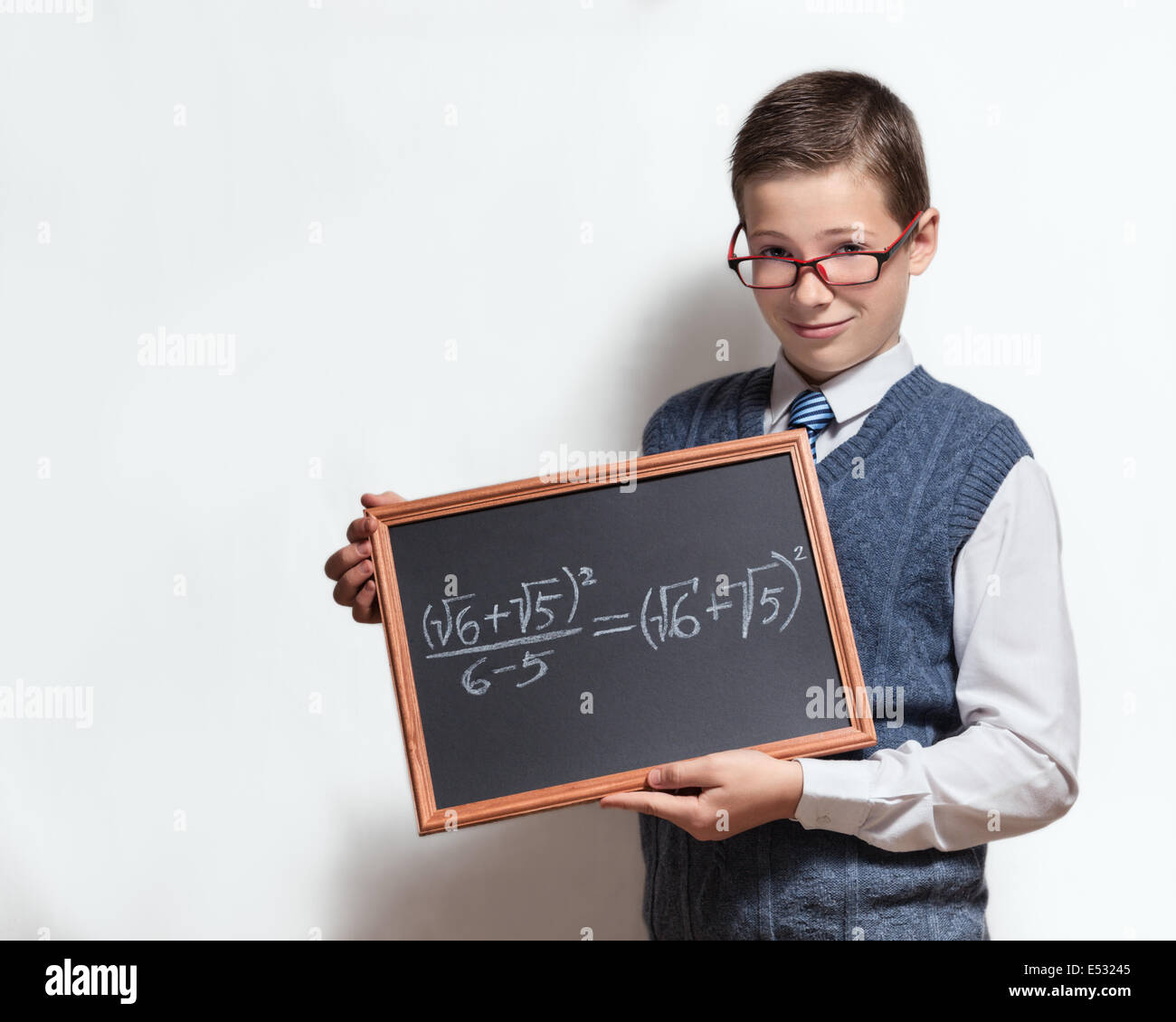 Smart schoolboy teenager in a glasses hold the chalkboard with the mathematical equation Stock Photo