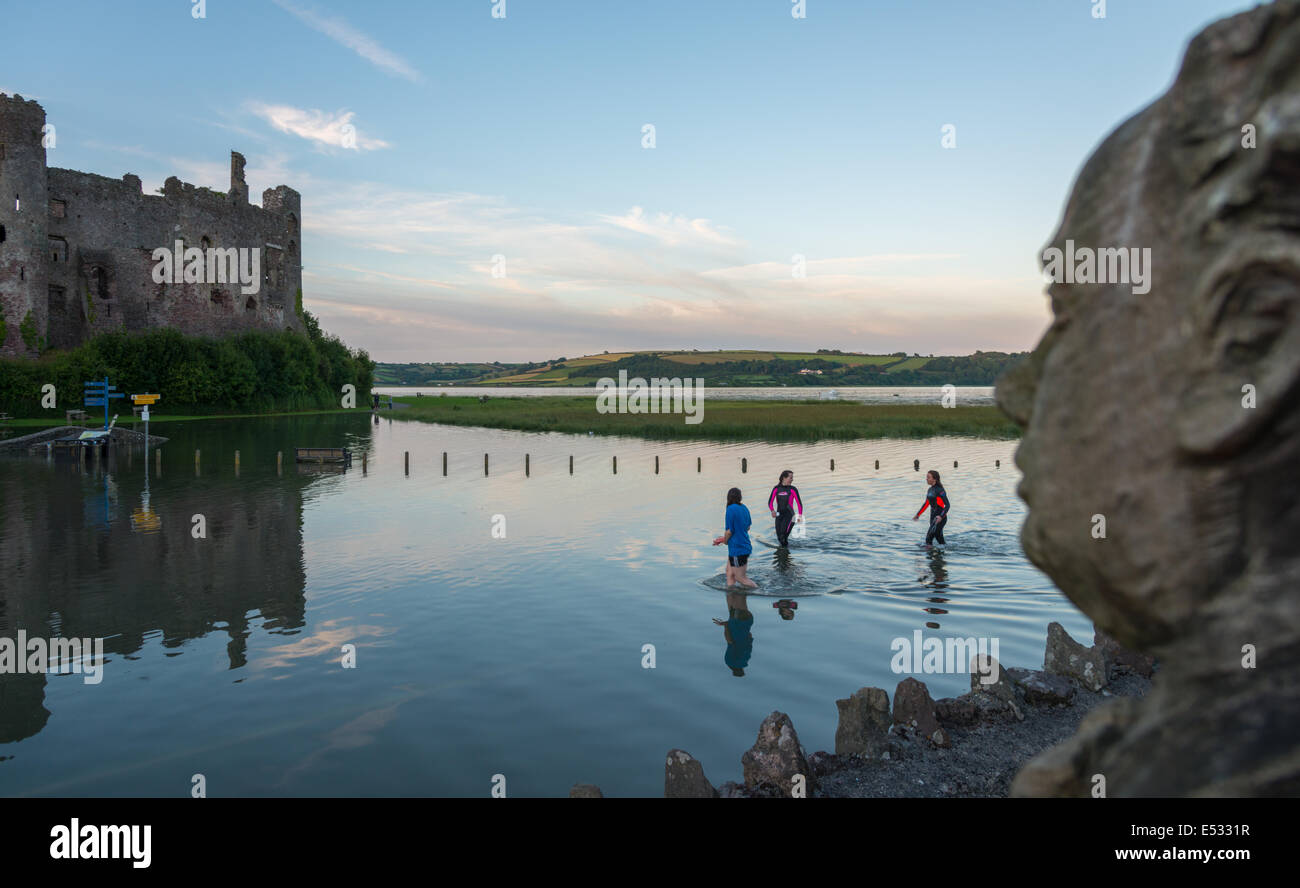 High water tide floods the car park in Laugharne, Carmarthenshire. Three people wade through the water. Stock Photo