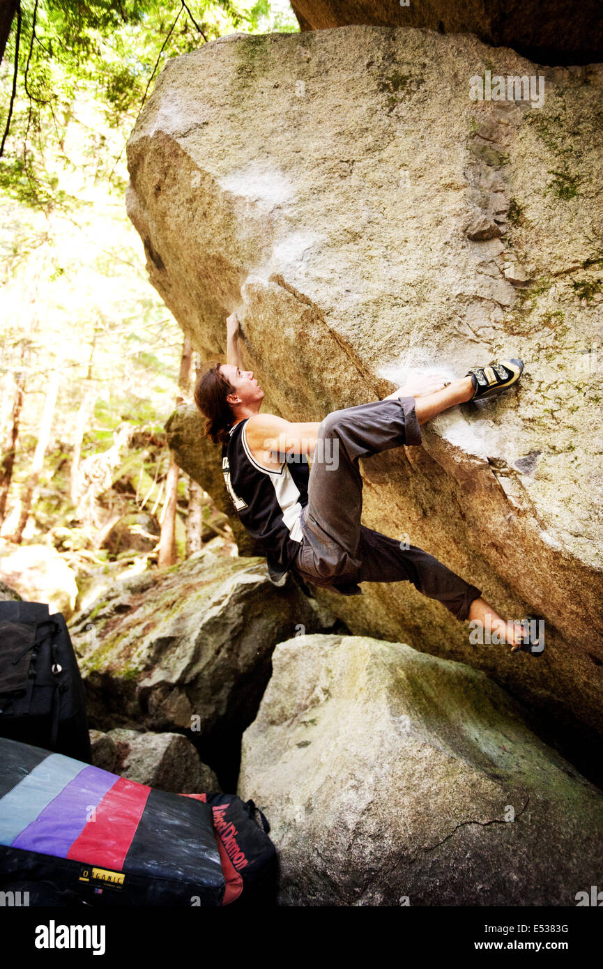 A man climbs a boulder, or bouldering, near the Stawamus Chief.  Squamish BC, Canada. Stock Photo