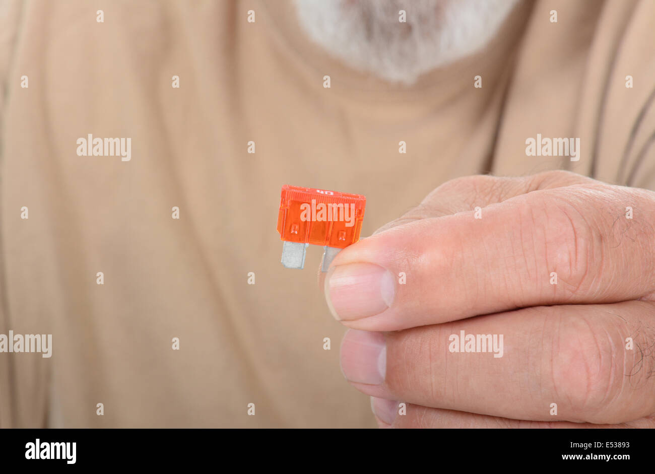 Closeup of a technician holding a fuse in his finger tips. The man is unrecognizable, with shallow depth of field. Stock Photo