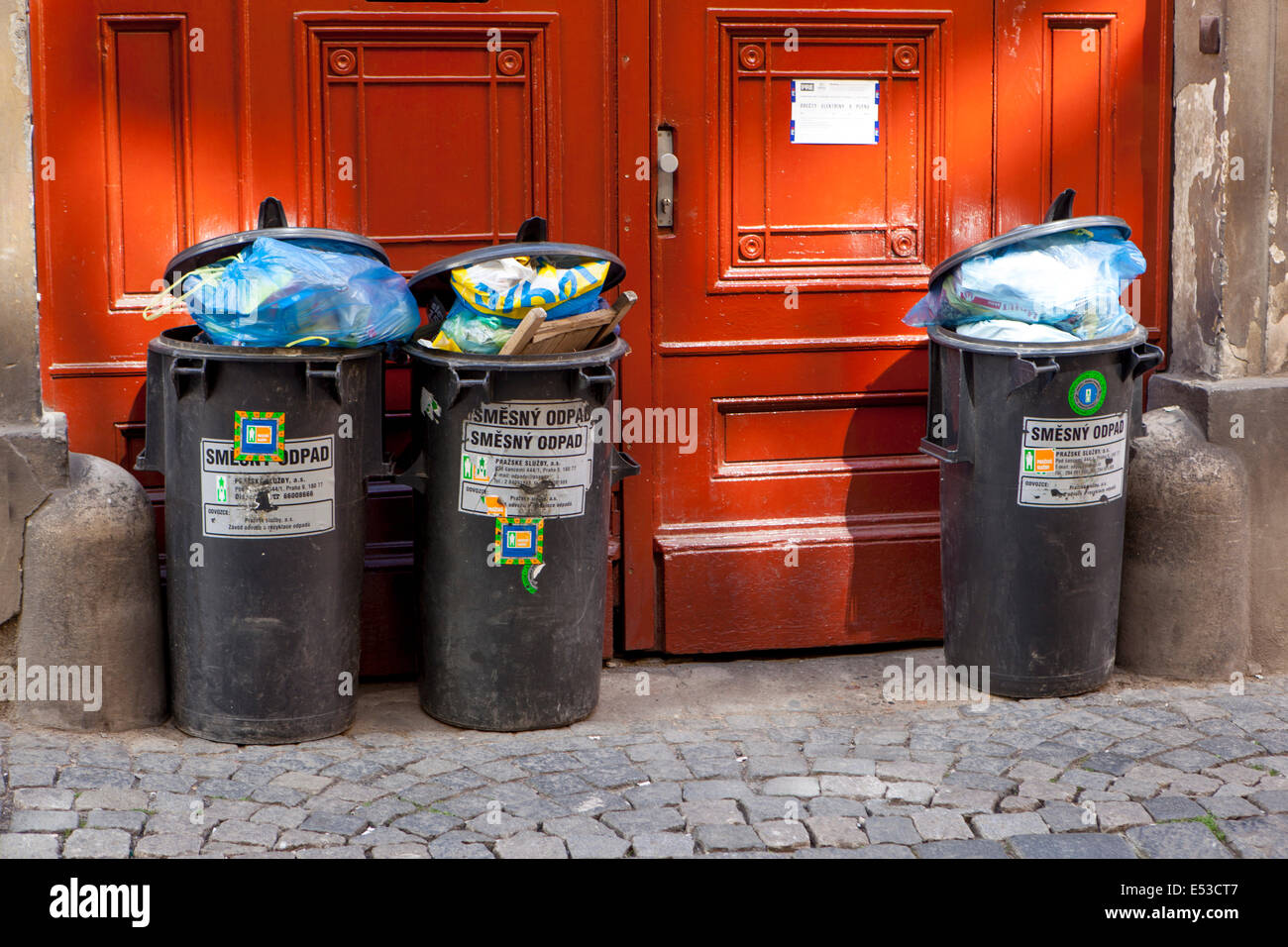 Full dustbins on the street, behind door Prague Czech Republic Stock Photo
