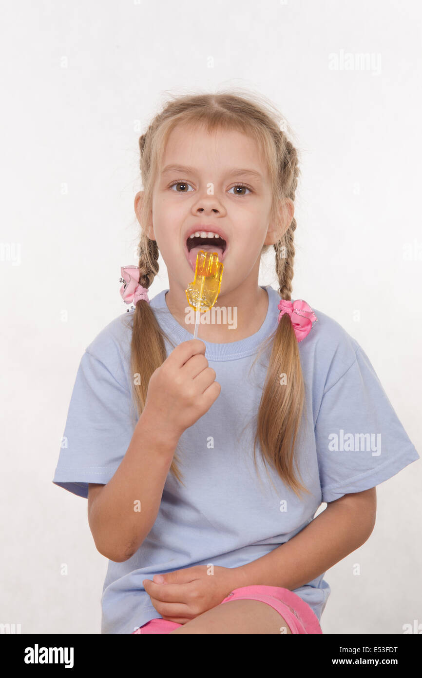 the five-year old girl enthusiastically eats candy Stock Photo