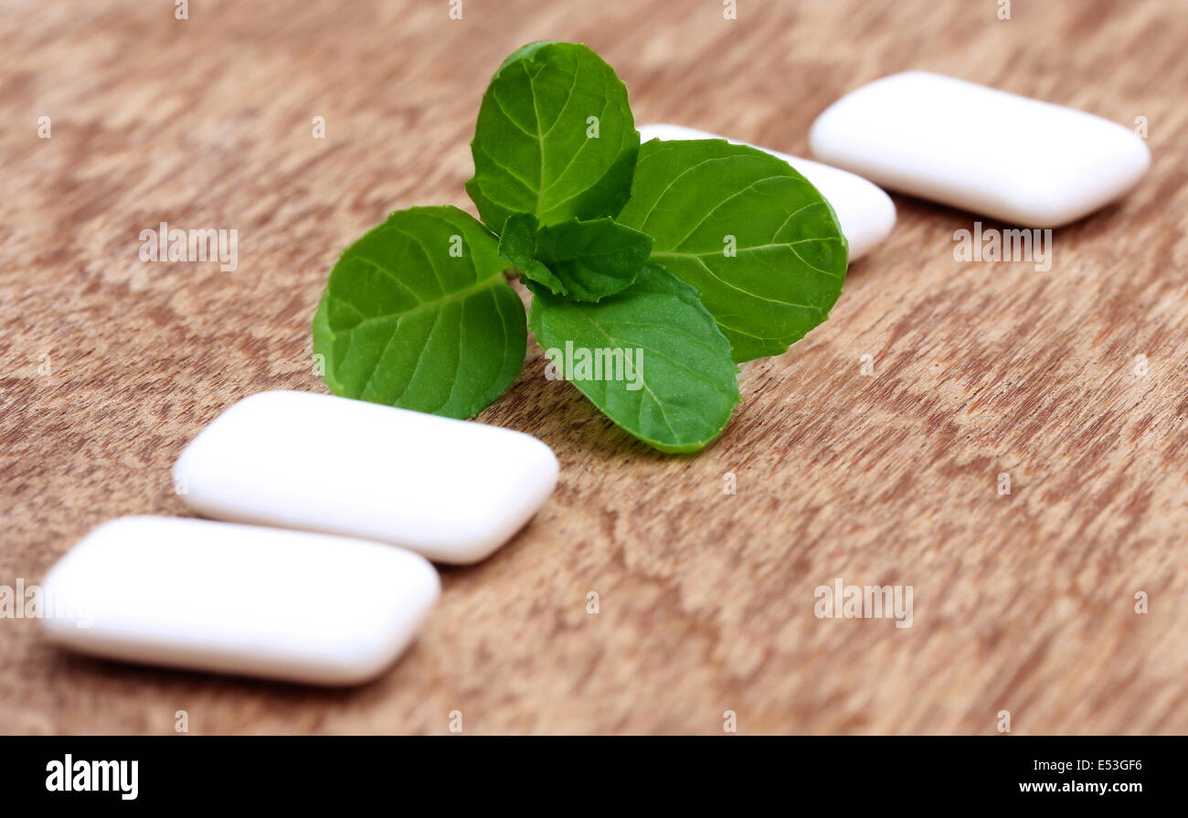 Chewing gum with mint leaves on wooden surface Stock Photo