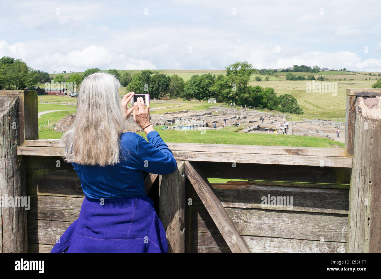 Female visitor to Vindolanda Roman Fort taking a photograph of the excavations Northumberland England UK Stock Photo