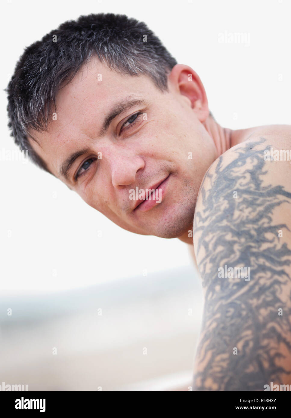 Portrait of young man with tattoo on his arm (forearm) on the beach. Stock Photo