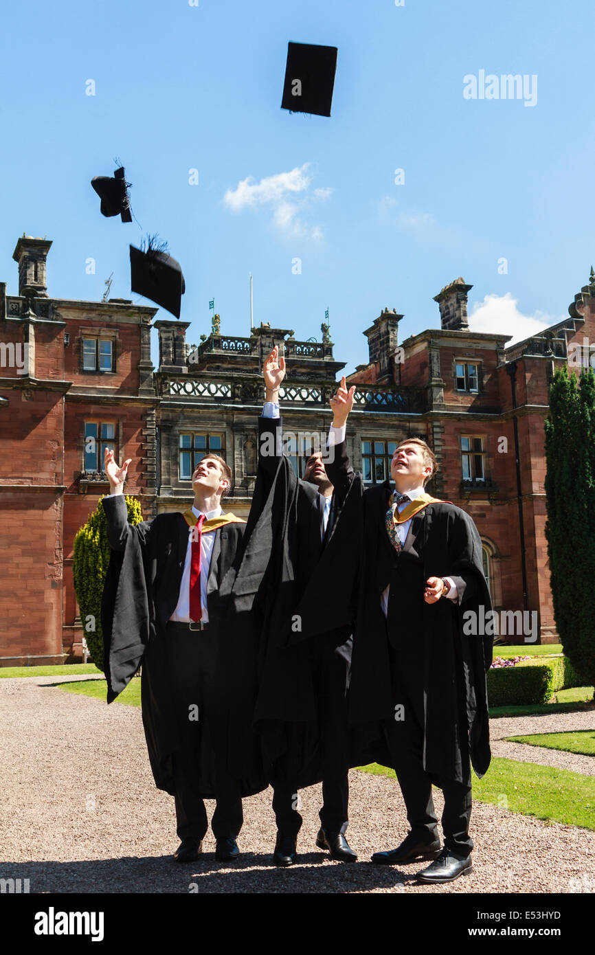 University students celebrate graduation in the traditional manner by tossing mortar boards into the air. Stock Photo