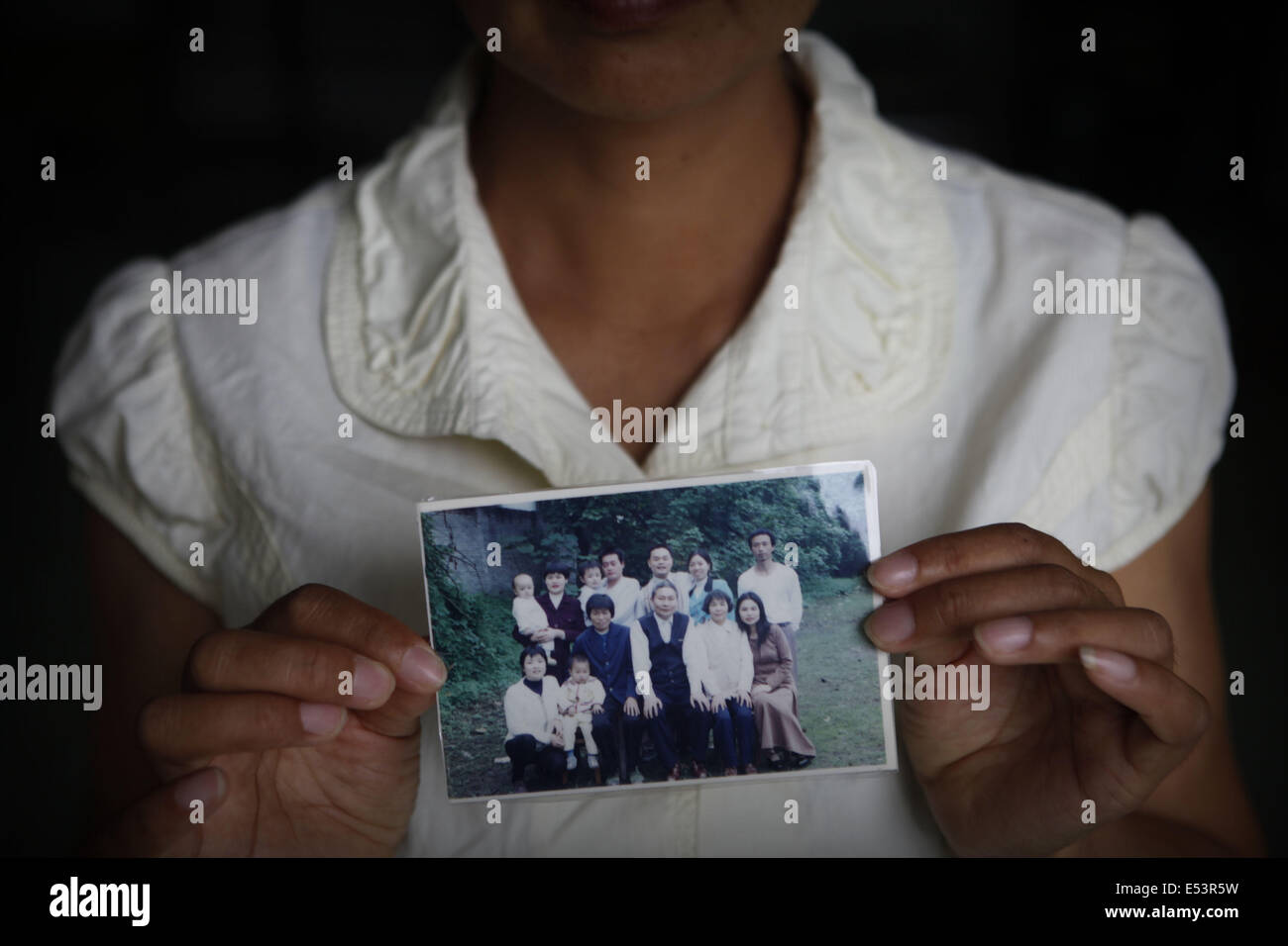 Bangkok, Thailand. 19th July, 2014. Jiang Kong, a Falun Gong practitioner and political refugee from China shows a family picture that was taken in her hometown back in China.Her father was tortured to dead by the infamous bureau 610, in one of the many black sites across China designed to make Falun Gong practitioners renounce their beliefs.The Falun Gong movement aka Falun Dafa movement is a banned movement in China that has tens of milions practitioners worldwide.In China followers get persecuted and send to labor camps, brainwash centras and concentration camps to renounce their beliefs. © Stock Photo