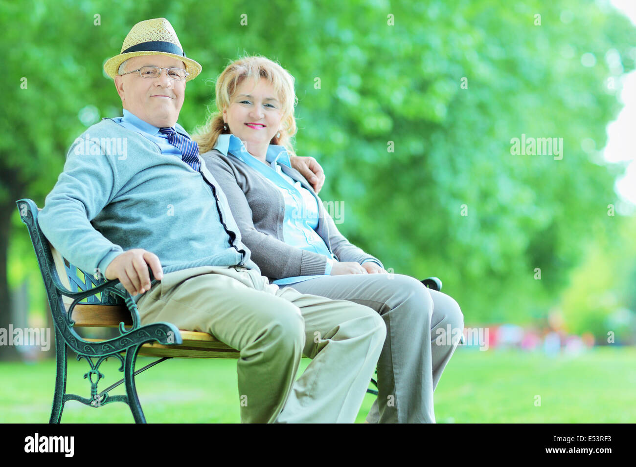 Mature couple posing in park seated on bench Stock Photo