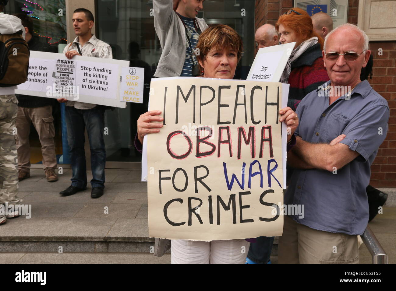 A woman holds up a sign with the words 'Impeach Obama for War Crimes' at an Anti-Fascist Resistance protest at the European Unio Stock Photo