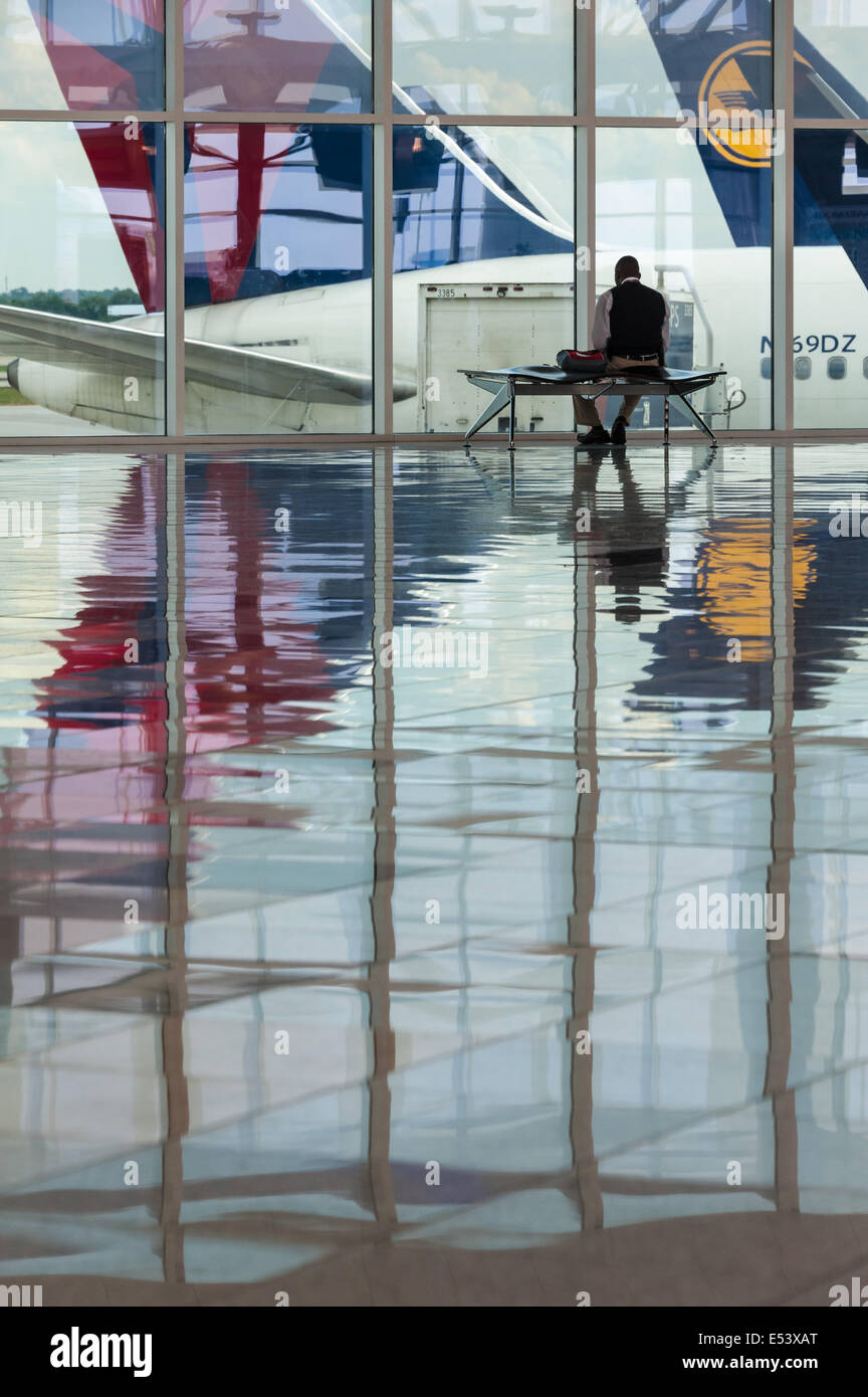 Seated man viewing passenger airliners at Atlanta International Airport in Atlanta, Georgia. (USA) Stock Photo