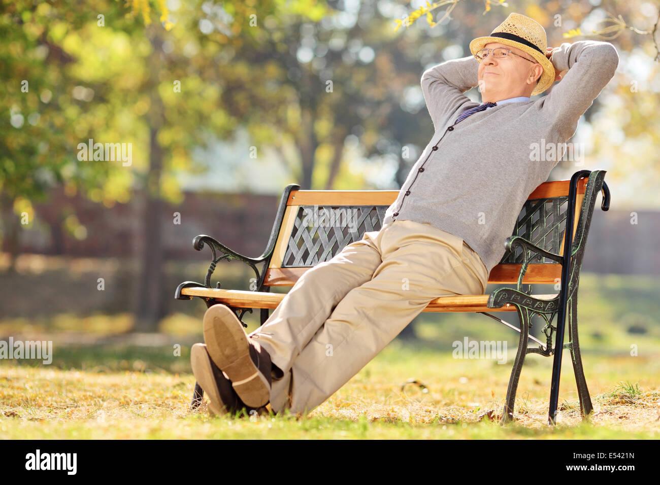 Relaxed pensioner sitting on a bench in park Stock Photo