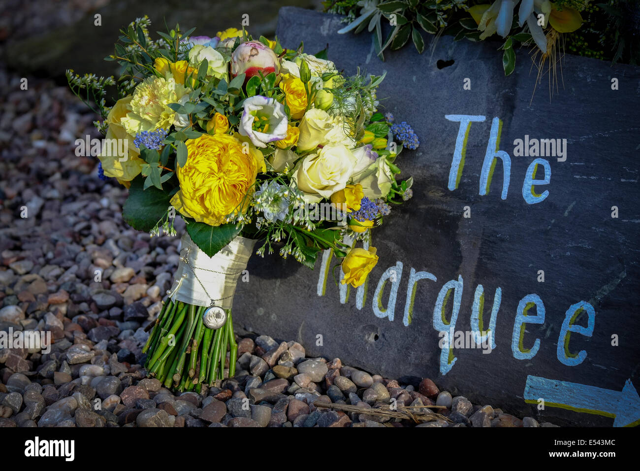 Wedding venue directions written on a slate tile with bridal bouquet Stock Photo