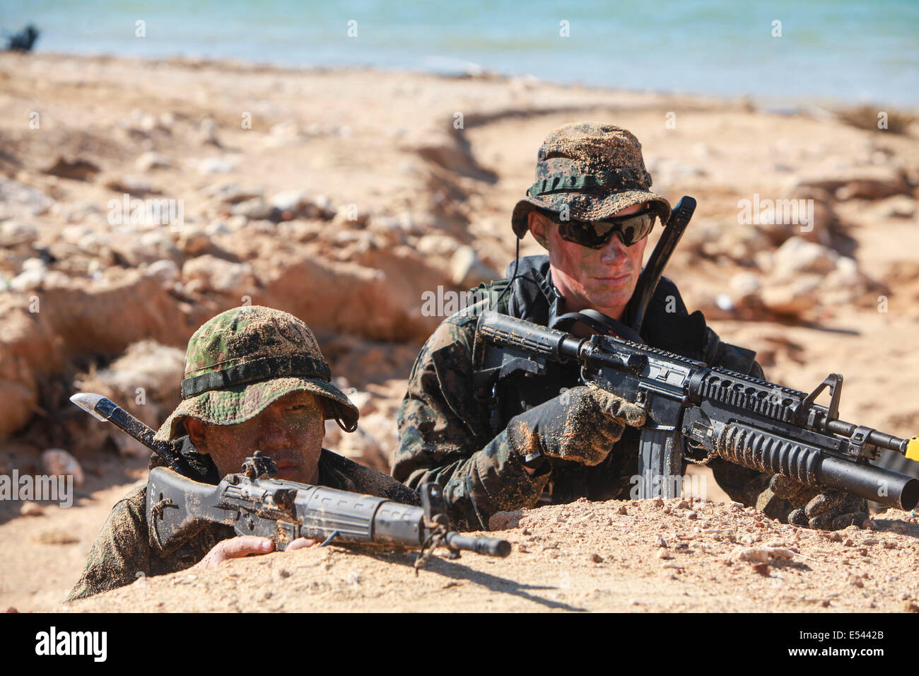 Japanese Ground Self-Defense and US Marine scout swimmer special operation soldiers hold the beach while practicing small unit level techniques as part of the Japan Observer Exchange Program at Kin Blue beach July 16, 2014 in Okinawa, Japan. Stock Photo