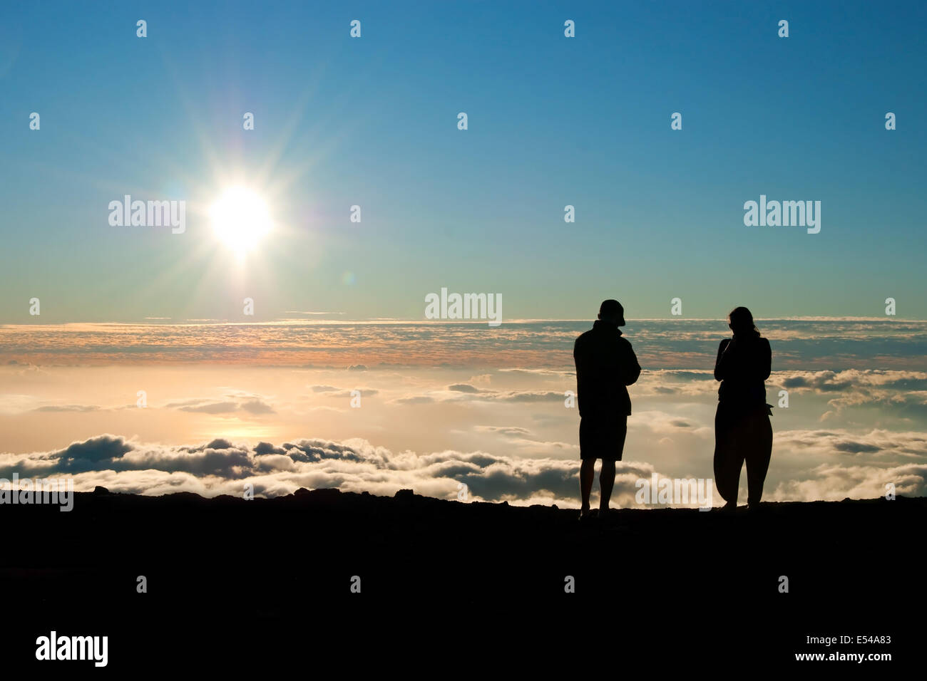 Tourist silhouette watching sunset on the top of  Haleakala volcano on Maui Hawaii Stock Photo