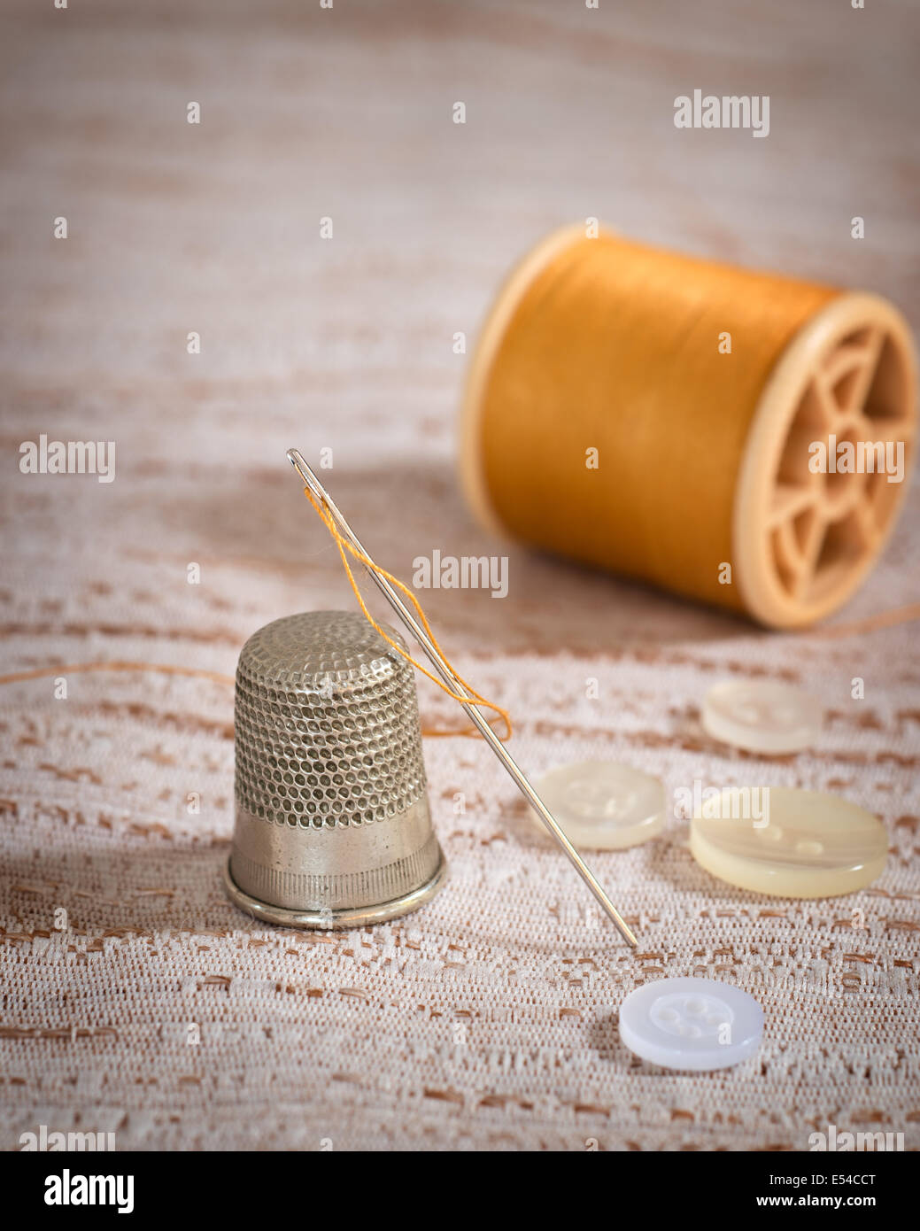 Threaded sewing needle with thimble and buttons Stock Photo