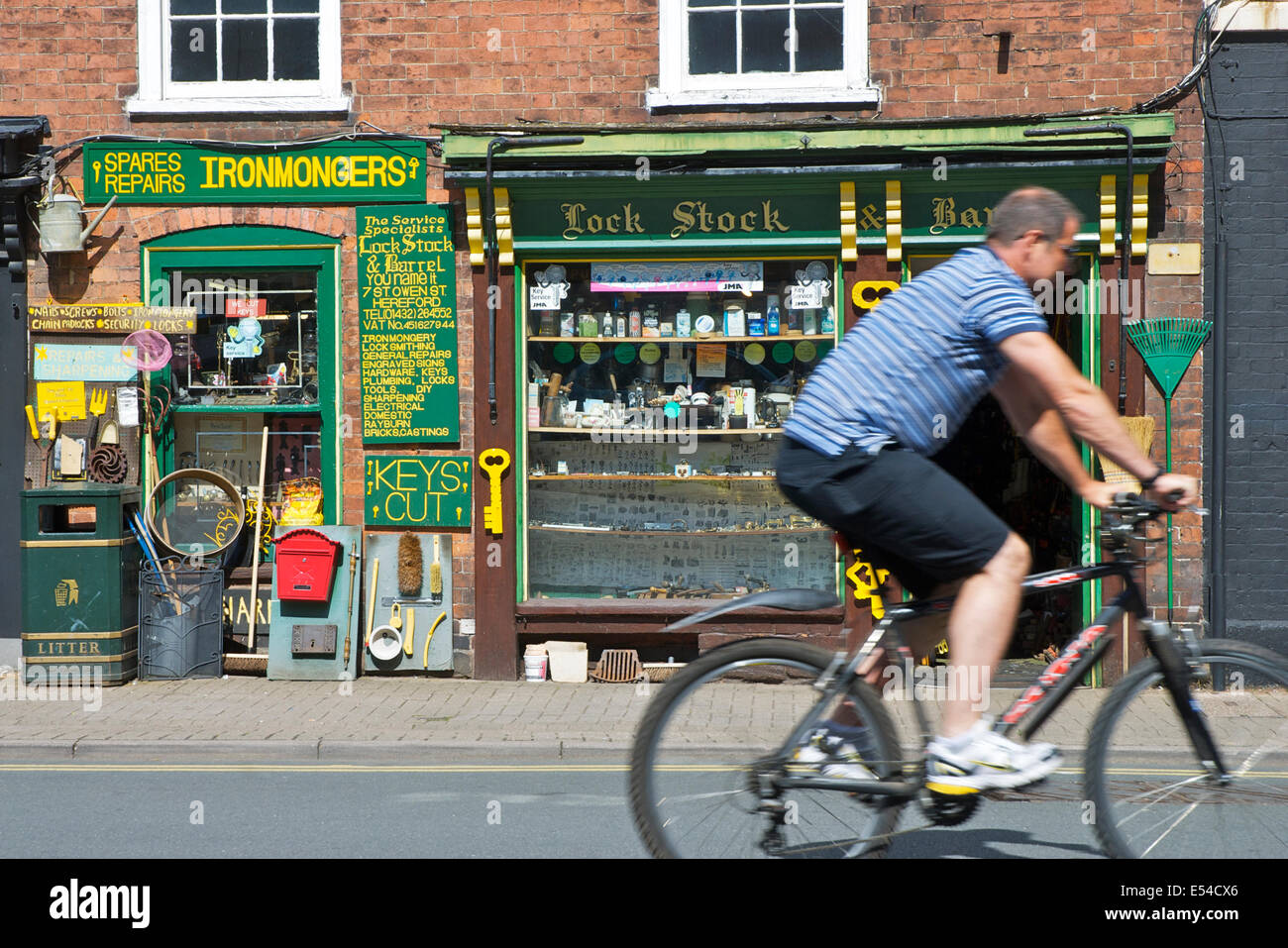 Man cycling past Ironmonger's shop in Hereford, Herefordshire, England UK Stock Photo