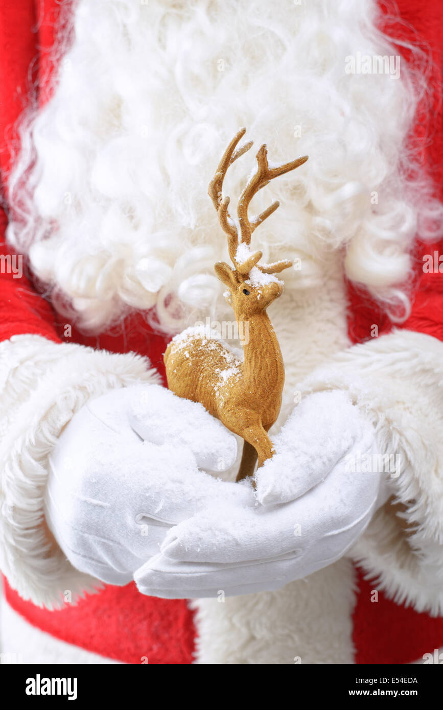 Father Christmas holding a reindeer ornament covered in snow Stock Photo