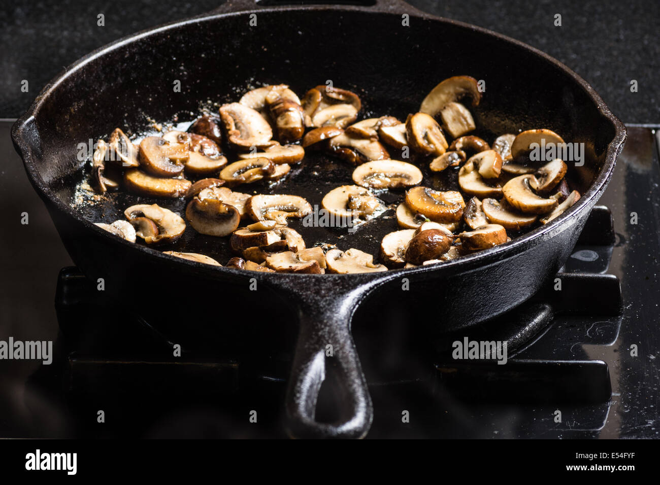 Sauteing sliced mushrooms in a cast iron skillet Stock Photo - Alamy