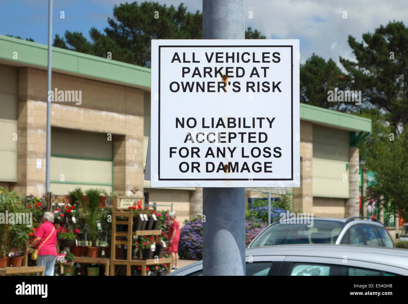 Vehicles parked at owners risk sign in a car park Stock Photo Alamy