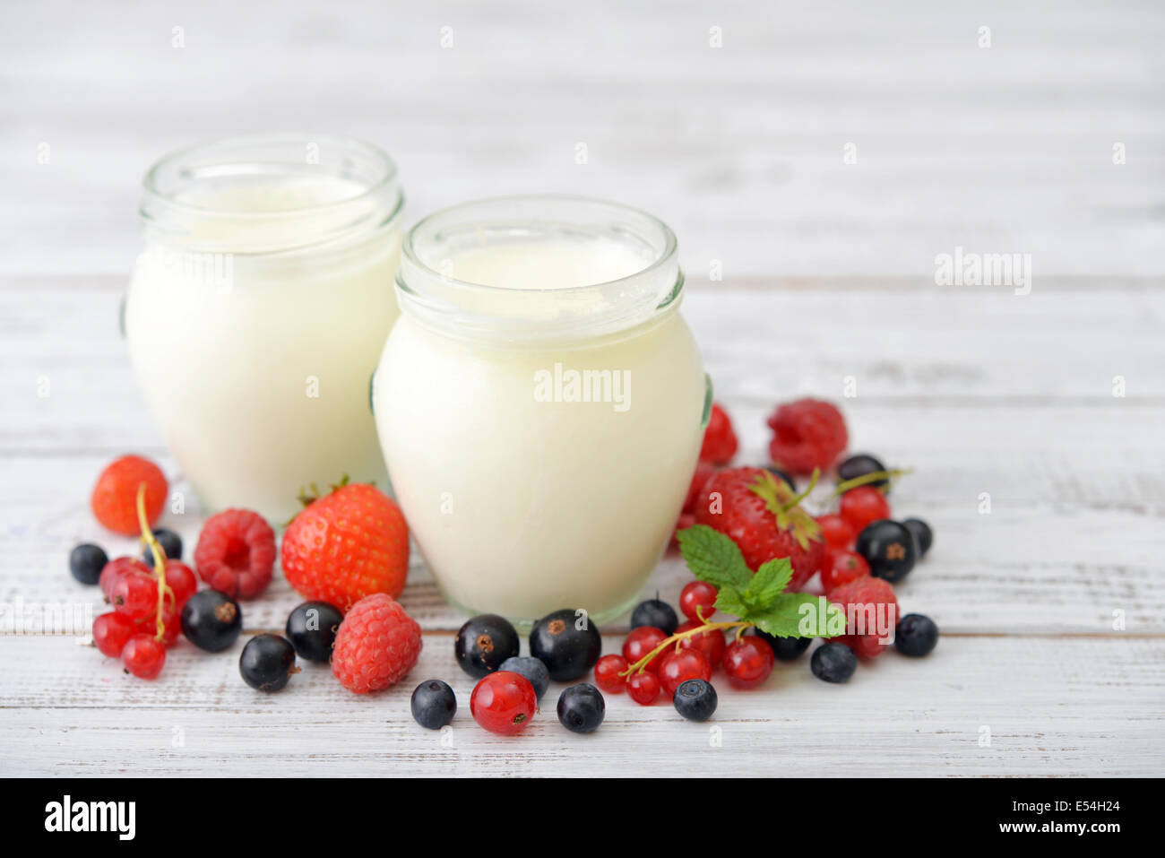 Yogurt with ripe fresh berry in jars on wooden background Stock Photo