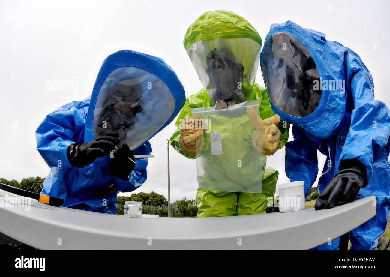 Emergency management specialists wearing HAZMAT Encapsulating Suits tag and bag an unknown substance during a training exercise  during a training exercise at the University of Mary June 27, 2014 in Bethany Beach, Delaware. Stock Photo