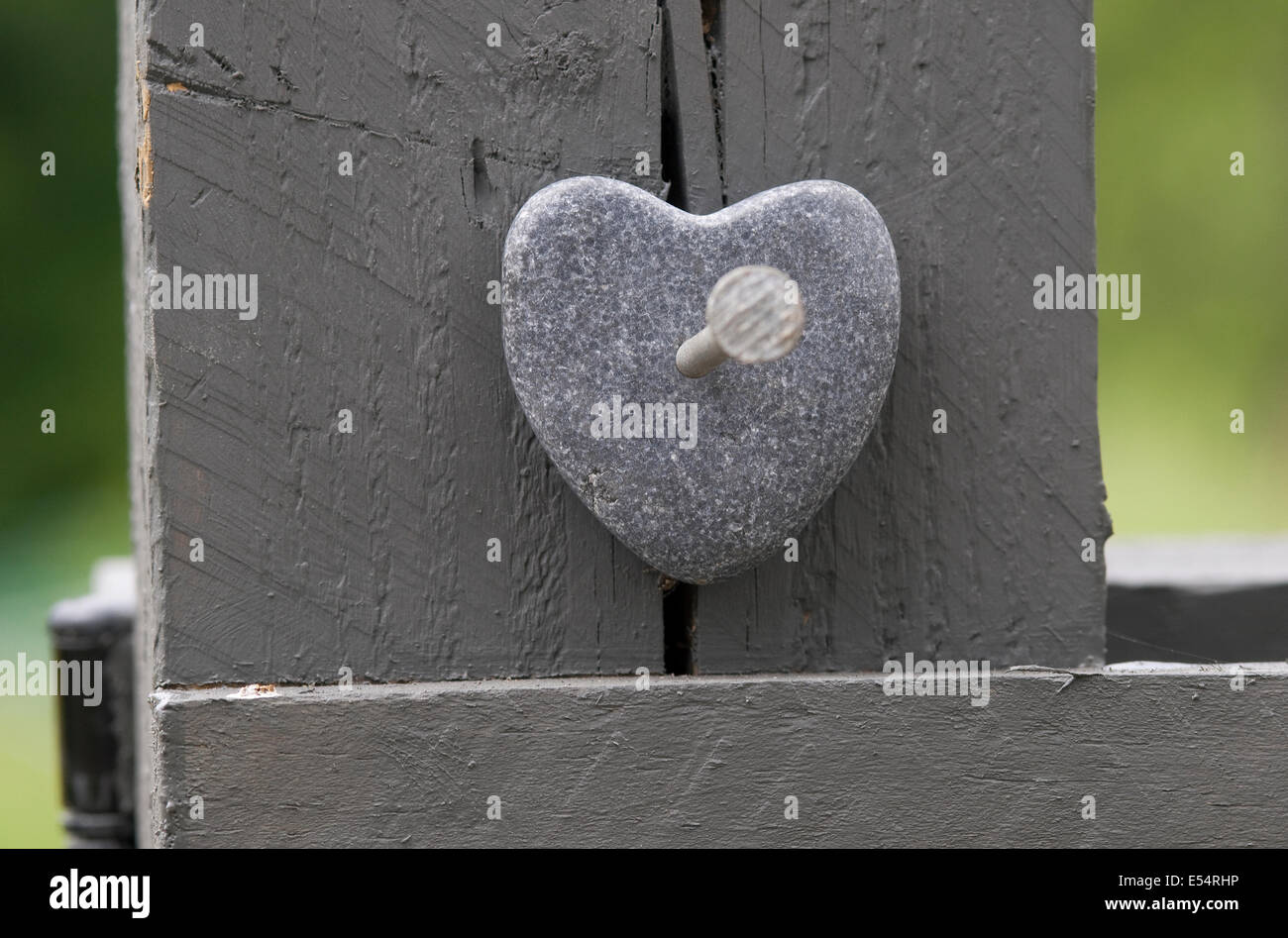 stone shaped heart nailed to grey fence post Stock Photo