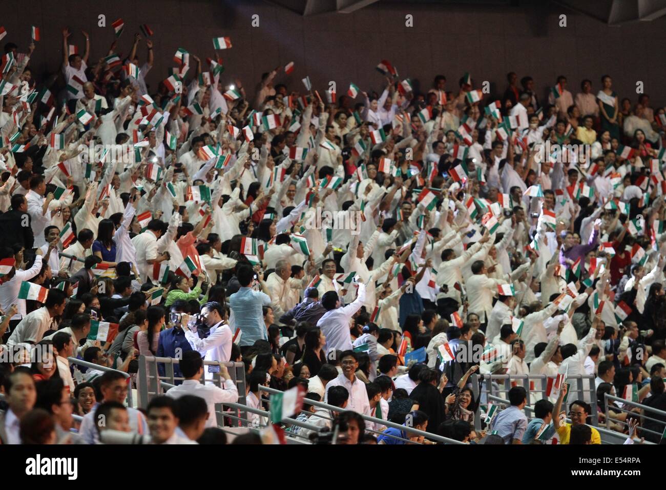 Bulacan, Philippines. 21st July, 2014. Bulacan, Philippines - Followers of Inglesia Ni Ciristo wave their flags during the inauguration of the Philippine Arena on July 21, 2014. The inauguration of the multi-purpose complex was lead by Inglesia Ni Cristo Executive Minister Brother Eduardo V. Manalo and President Benigno Aquino III. The Philippine Arena, touted as the world's largest domed arena with a 55,000 seating capacity whose construction cost over $200 million is built to withstand strong earthquakes and super typhoon winds. Credit:  ZUMA Press, Inc./Alamy Live News Stock Photo