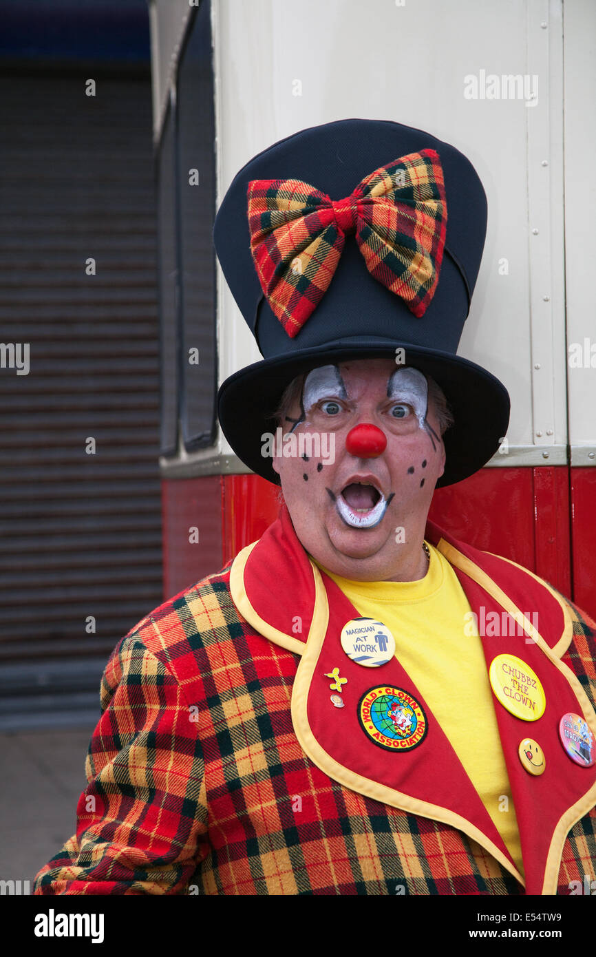 Professional Circus clown, fun, funny, happy, carnival, party, costume, humor, entertainment,  celebration, red face,  comic, colorful, character, art, wig.  Clowning in a funny Top Hat and tartan suit in Fleetwood, Lancashire. Performer Paul Davies expressions of sadness, surprise & humor.  Colorful Clown costume & art deco top hat and Children's Entertainer at the Festival of Transport, UK Stock Photo