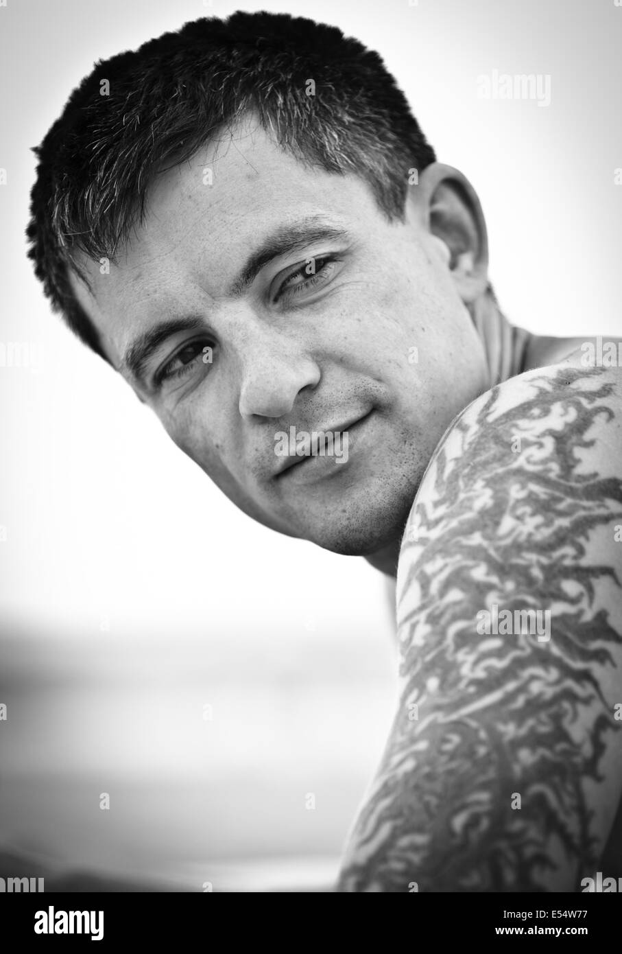 Portrait of young man with tattoo on his arm (forearm) on the beach. Stock Photo