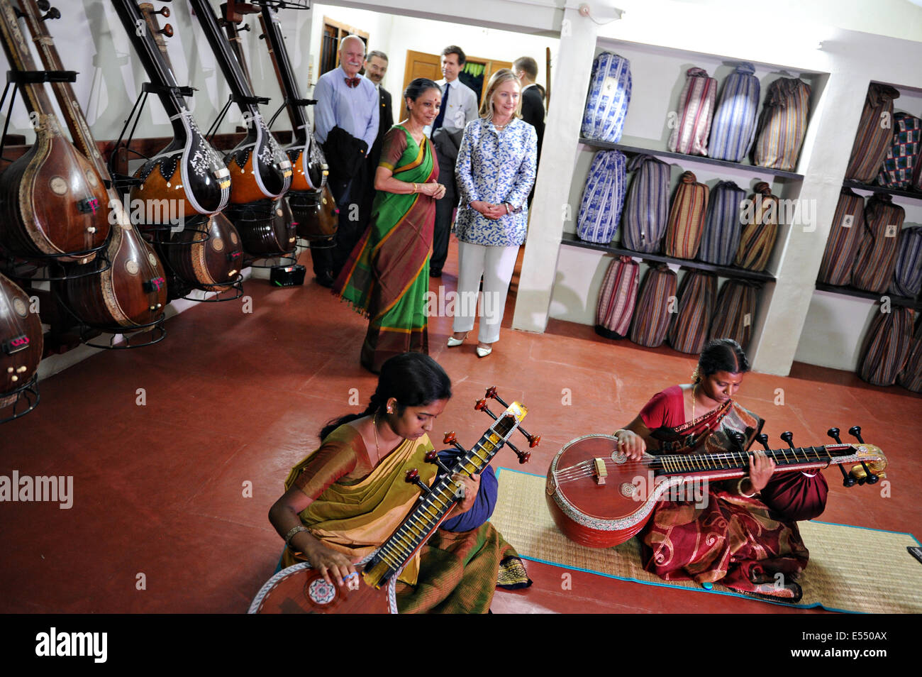 US Secretary of State Hillary Rodham Clinton watches two women practice playing the veena, a traditional Indian stringed instrument during a visit to Kalakshetra cultural academy July 20, 2011 in Chennai, India. Stock Photo