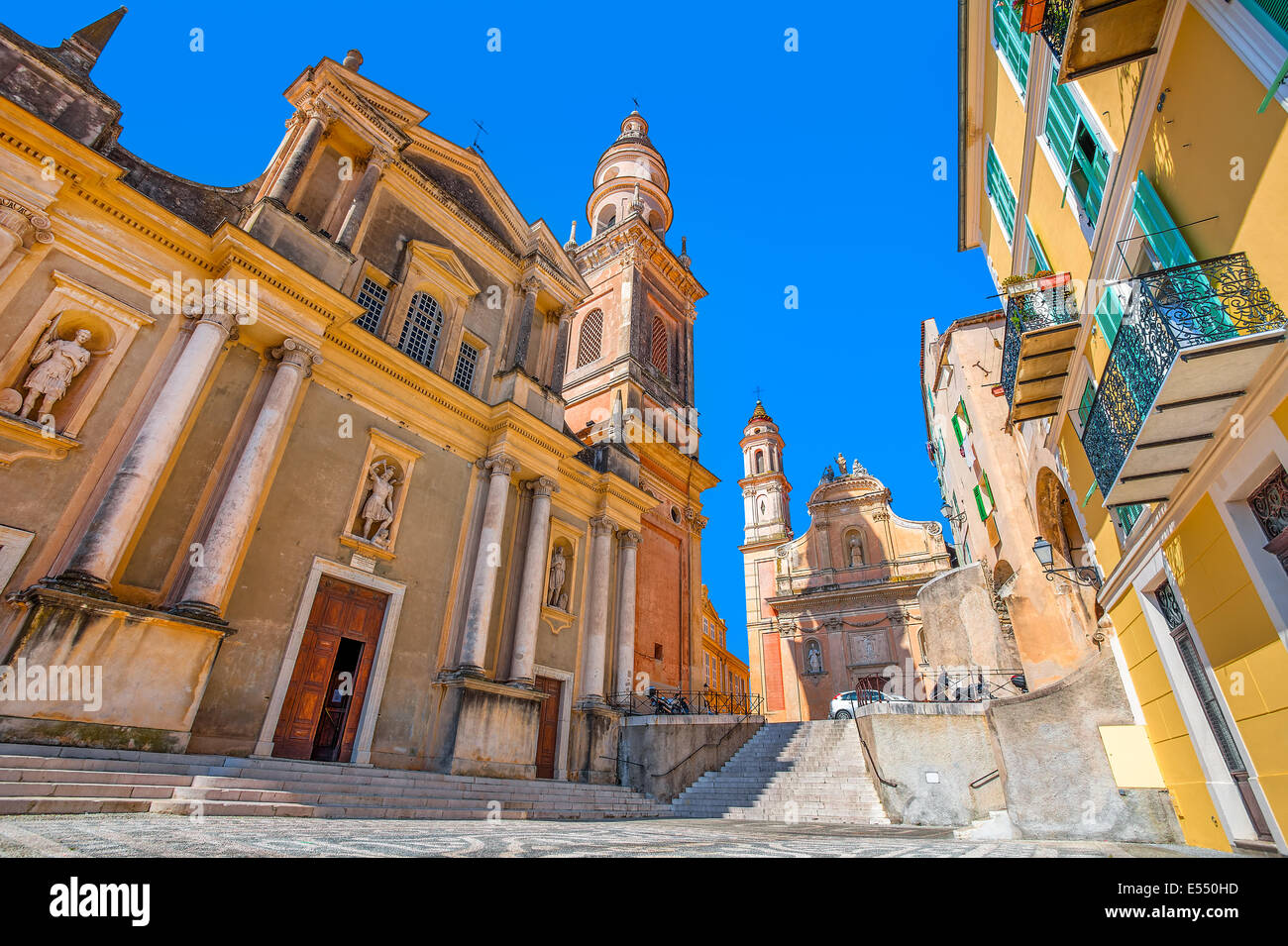 Basilica of Saint Michael Archange on small town square under blue sky in Menton, France. Stock Photo