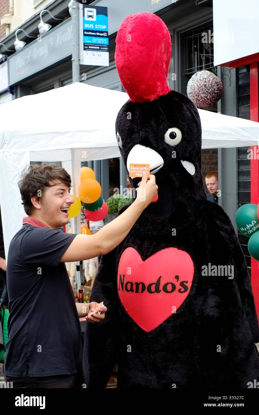 laughing staff member with giant chicken costumed colleague from nandos at the southsea food fair festival 2014 england uk Stock Photo