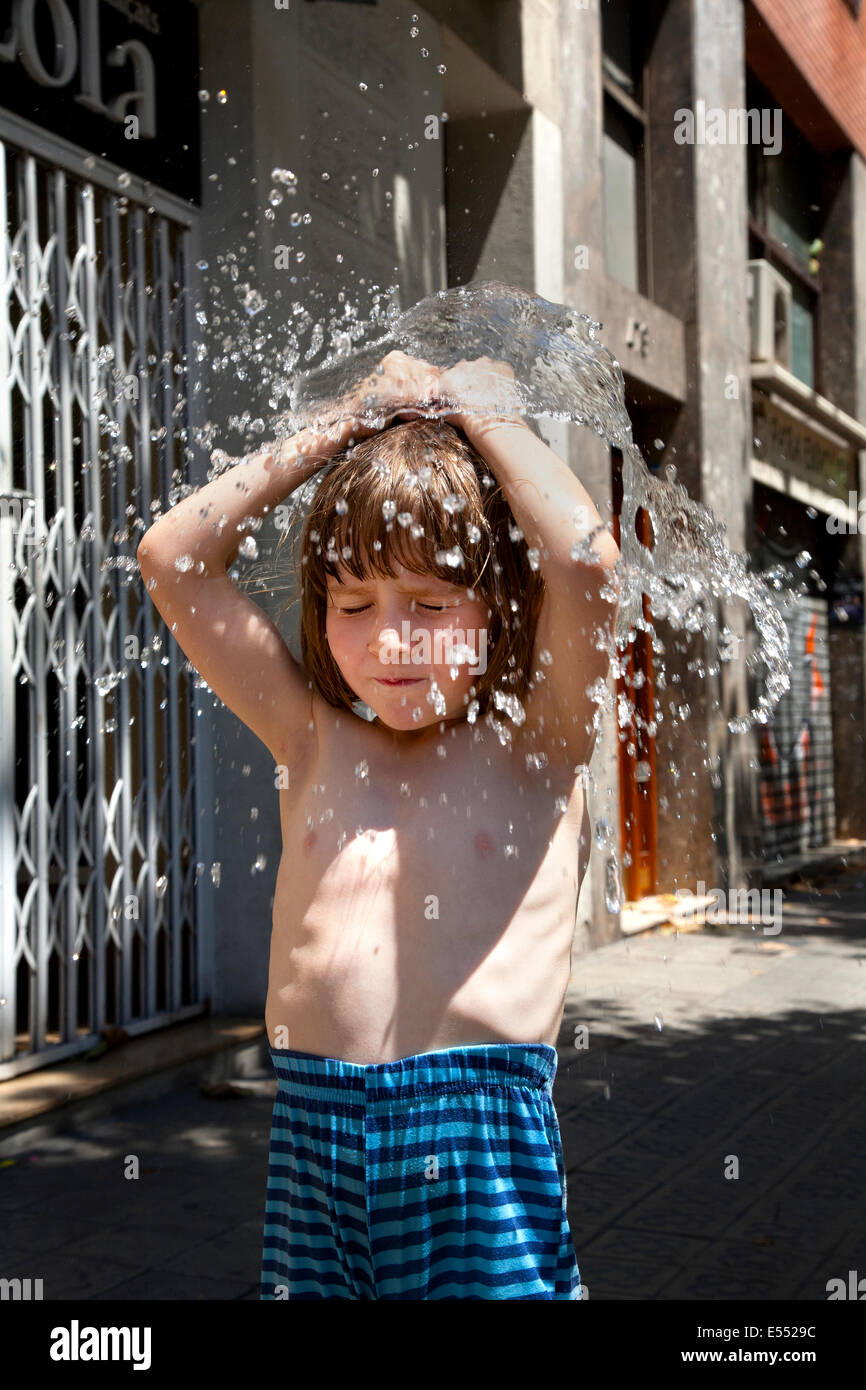5 year old boy exploding water balloon over his head. Stock Photo