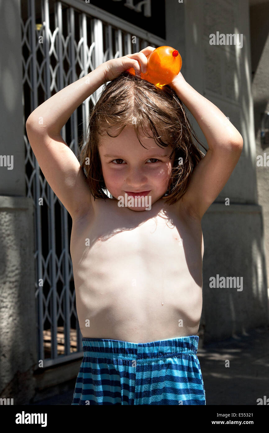 Boy holding water balloon over his head. Stock Photo