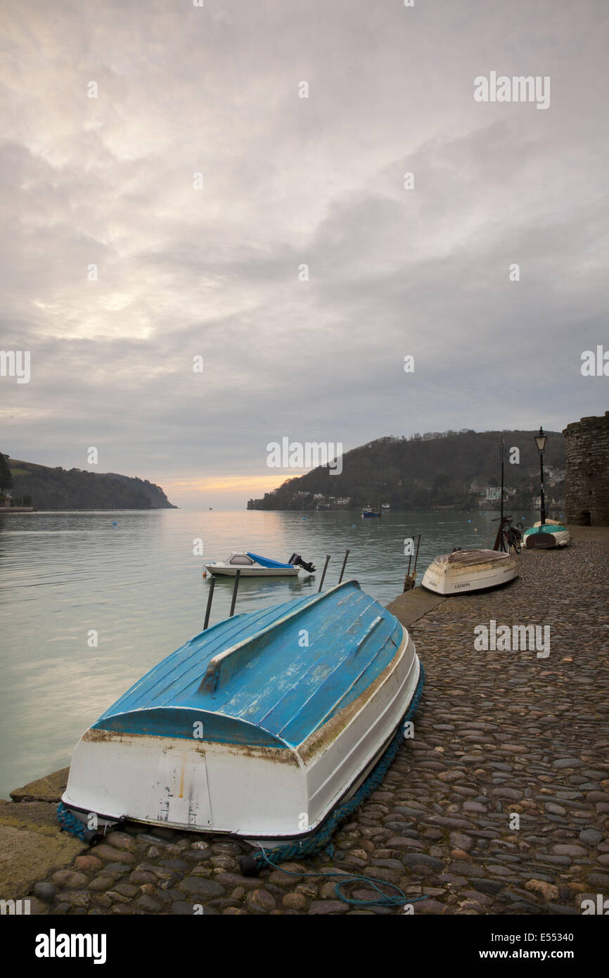 Small dinghies laying upside down on cobbled quay, with overcast sky at
