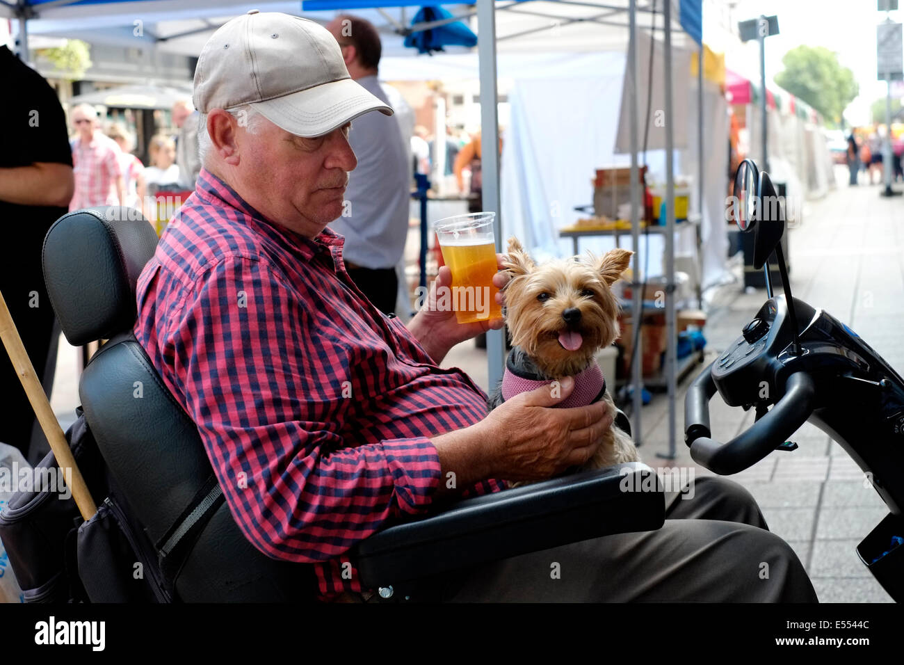 disabled man on mobility scooter with his dog enjoys a beer at the southsea food fair festival 2014 england uk Stock Photo