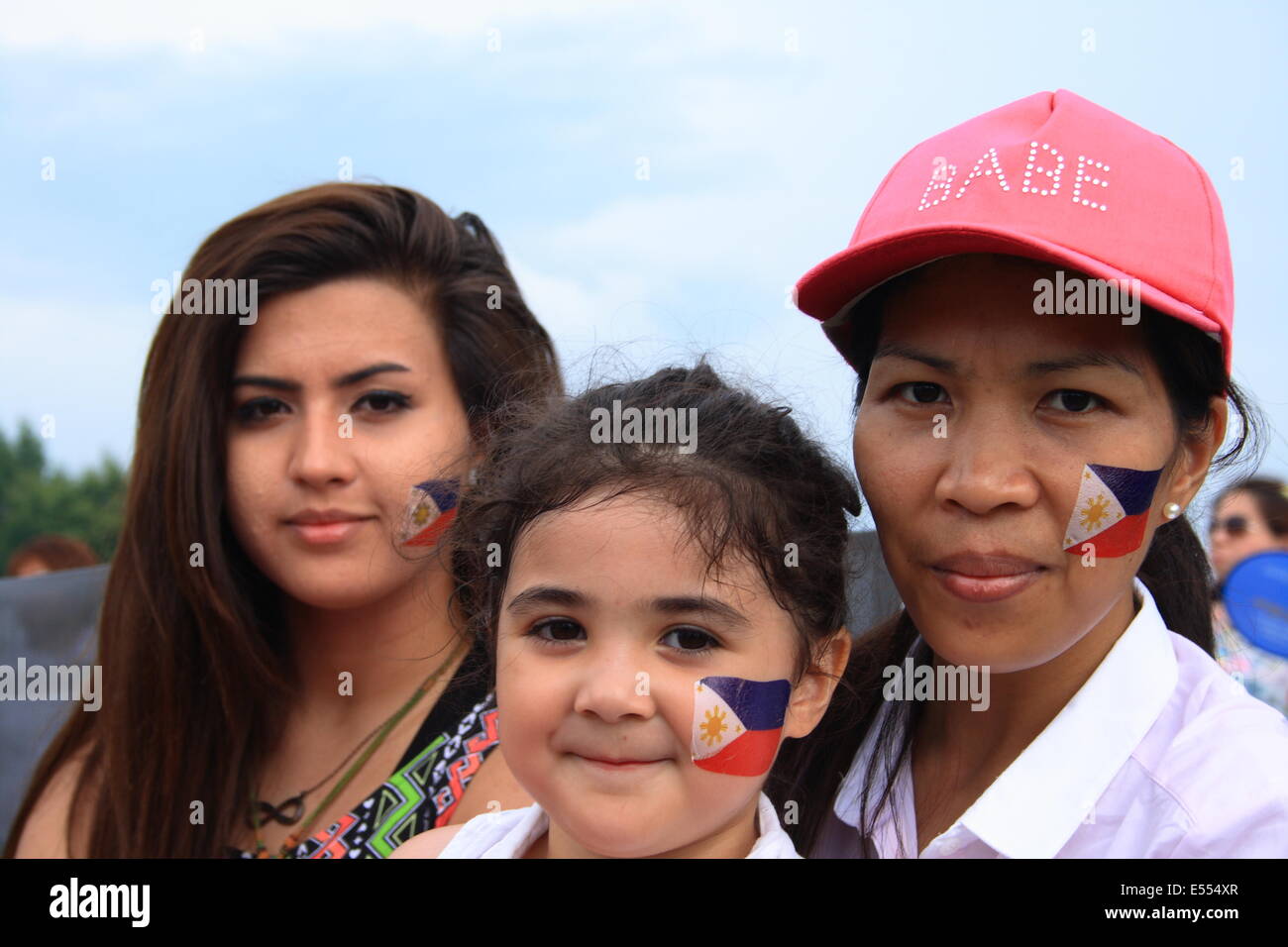 Walton, Surrey, UK. 20th July, 2014. A British Filipino family of a mother and her two daughters enjoying the fiesta having had their faces painted with the philippine flag depicting the sunshine symbol. Credit:  Paul Hamilton/Alamy Live News Stock Photo