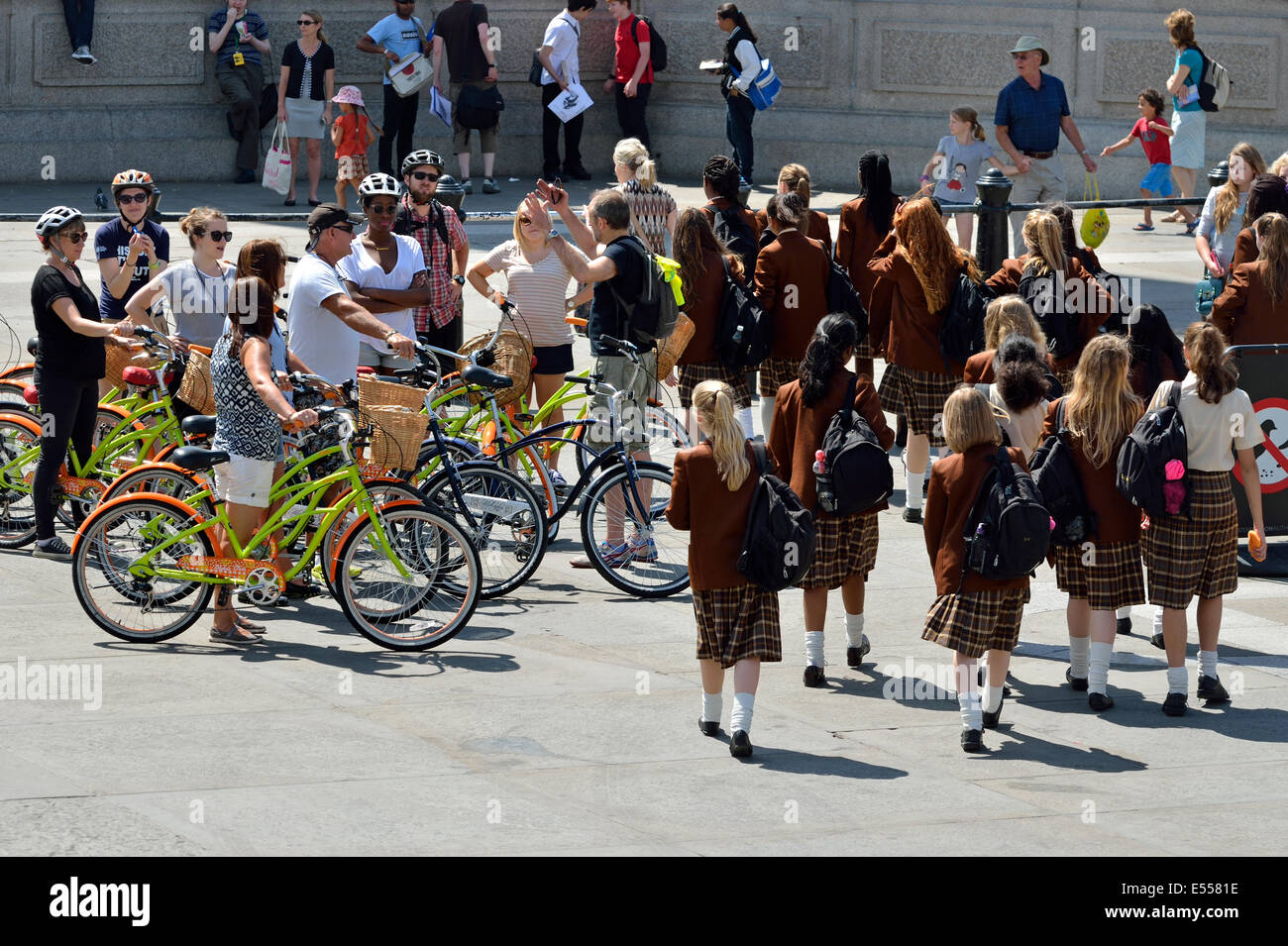 London, England, UK. Trafalgar Square: Schoolgirls in uniform on a school trip, and an organized cycling tour Stock Photo