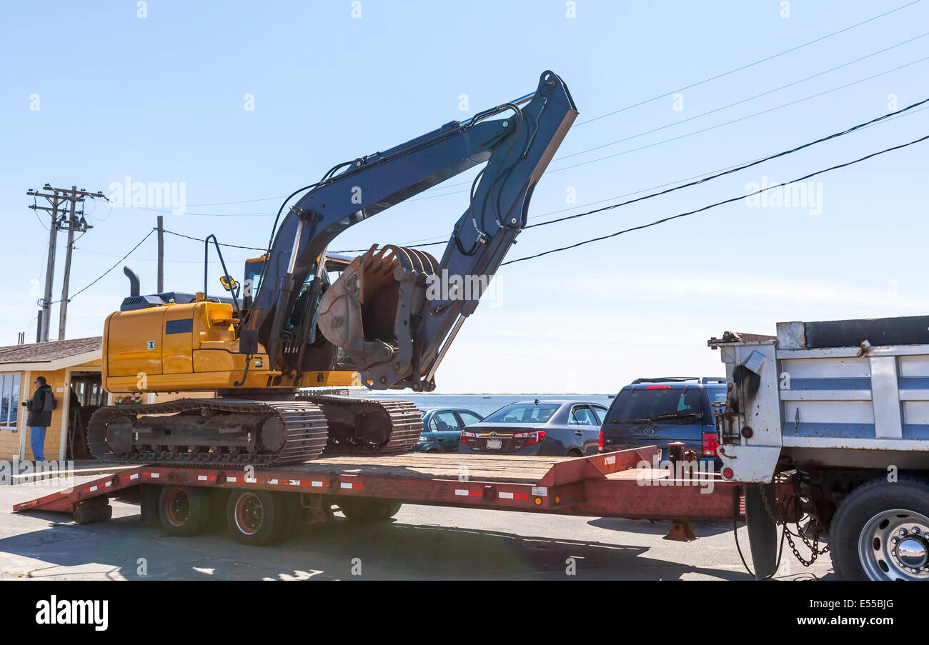 An Excavator Construction Equipment being loaded unto a flatbed for removal from worksite. Stock Photo