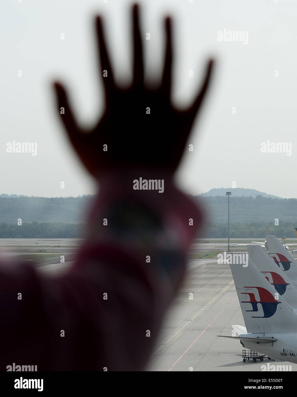 Putrajaya, Malaysia. 19th July, 2014. An unidentified child's hand is silhouetted as she leans on the window to see Malaysia Airlines planes taxied on the tarmac of Kuala Lumpur International Airport as it enters the second day of the of the Flight 17 crash in Ukraine in Sepang, Malaysia, Saturday, July 19, 2014. The Malaysia Airlines jetliner was carrying 298 people when it was shot down over eastern Ukraine. Credit:  Joshua Paul/NurPhoto/ZUMA Wire/Alamy Live News Stock Photo