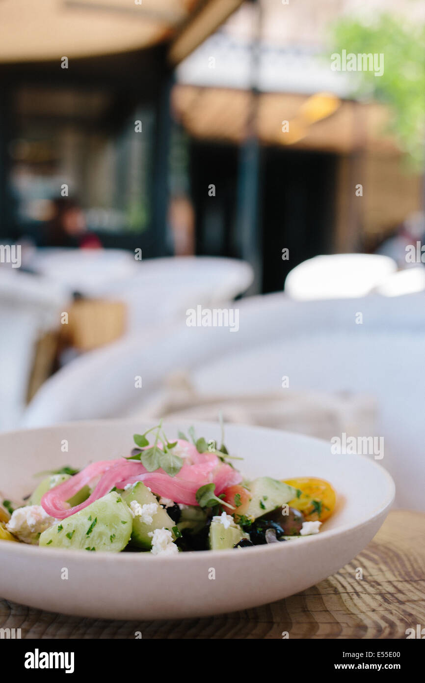 Cucumber salad with feta and tomatoes on wood table with blurred background Stock Photo
